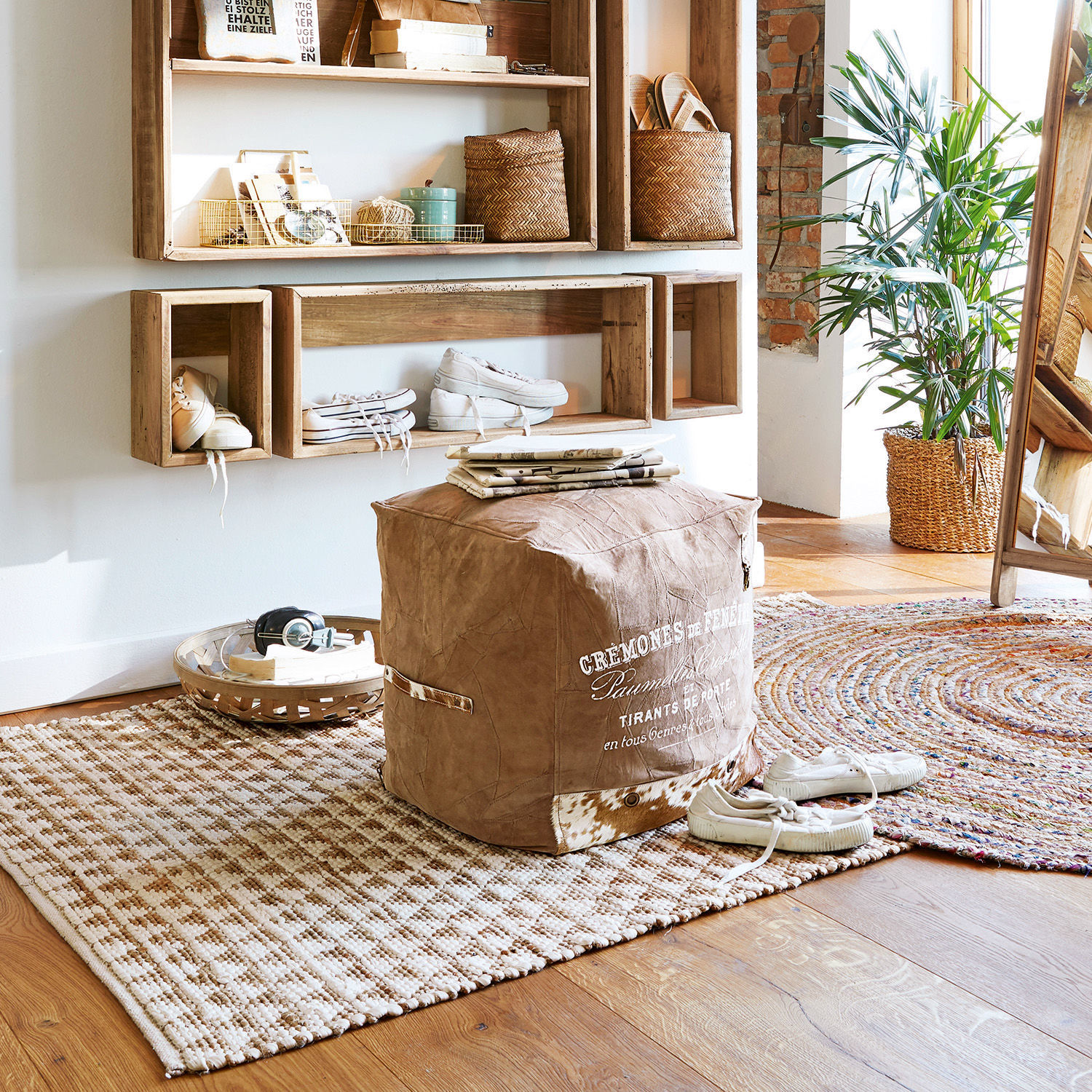 Gemütliches Zimmer mit braunem Stoffpouf und weißen Sneakers auf Teppich aus Naturfasern
