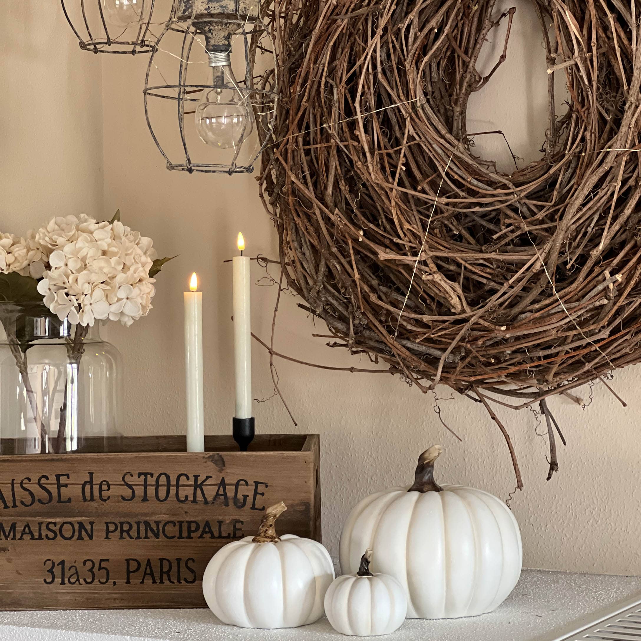 Herbstliche Dekoration mit weißen Kürbissen, Holzkiste und natürlichem Zweigkranz für Zuhause