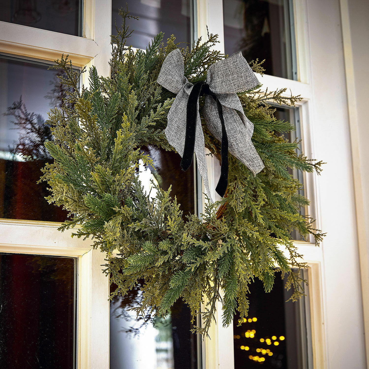 Kranz Julien Weihnachtskranz aus grünen Zweigen mit grauer Schleife an weißer Haustür