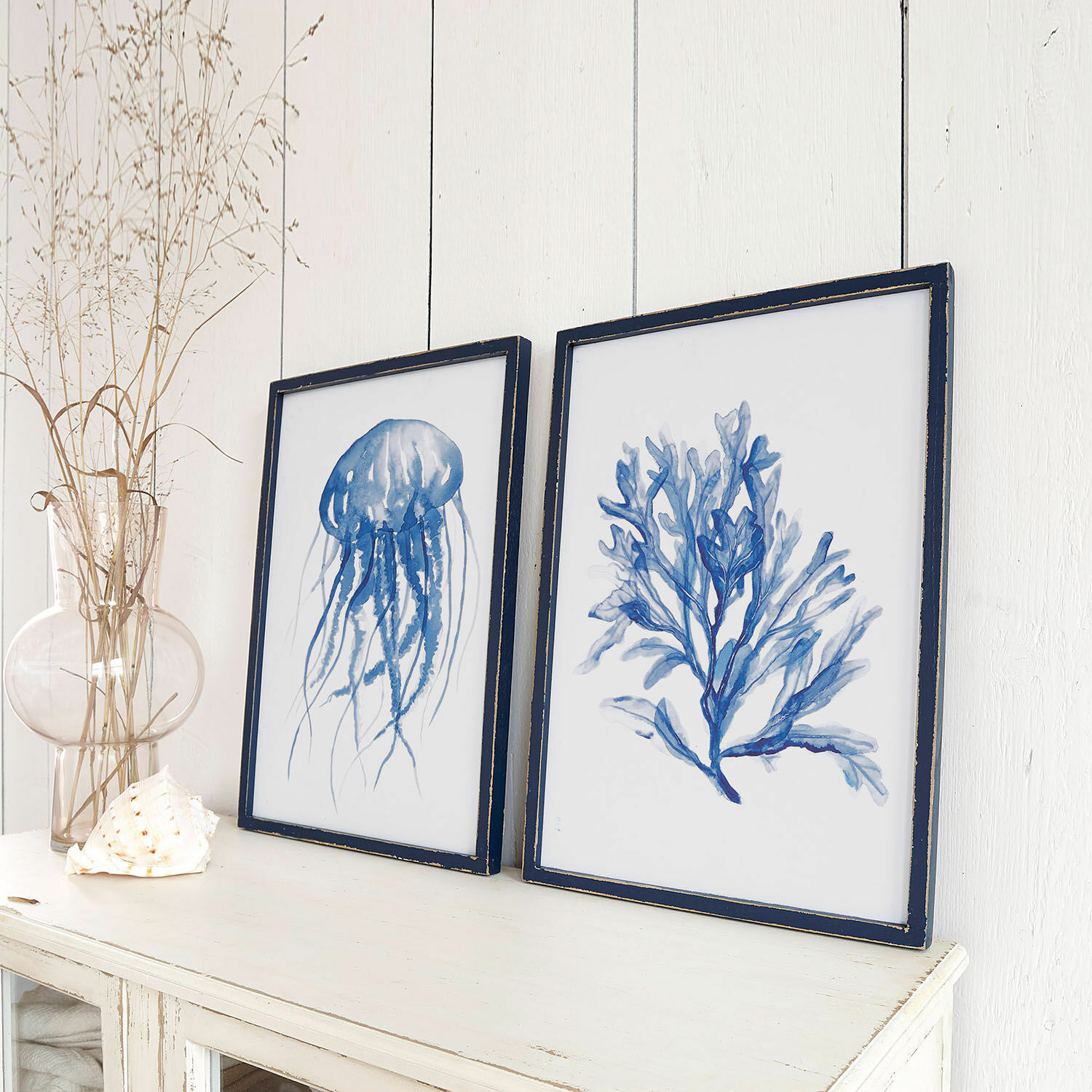Wandbild 2er Set Dewey Zwei maritime Bilder in blauen Rahmen auf weißem Sideboard, stilvolle Wohnraumdekoration.
