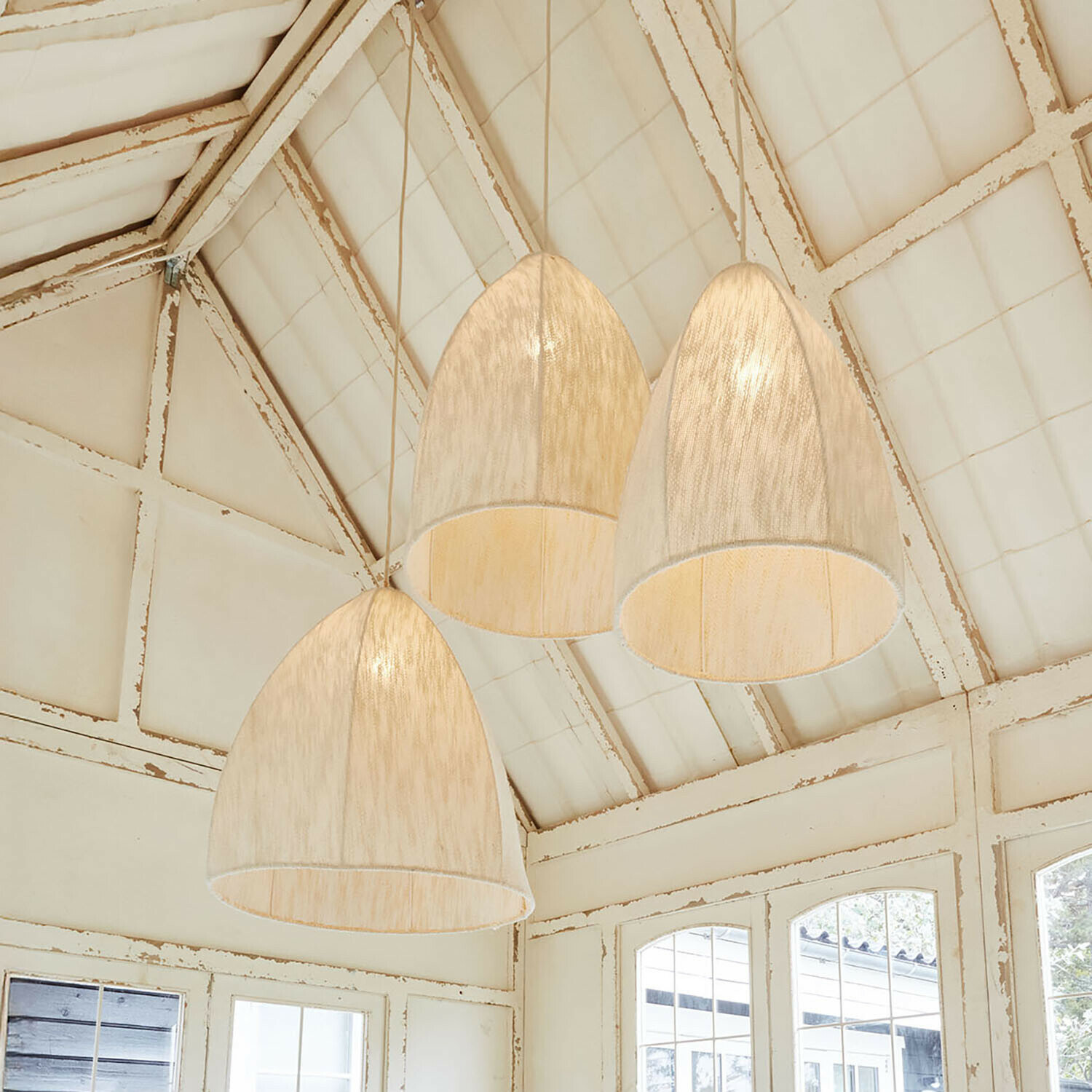 Drei hängende Lampen aus hellem Stoff in Glockenform in rustikalem Raum mit weißer Decke