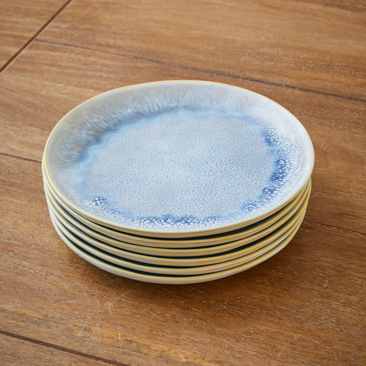 Sechser-Set Keramikteller in Blau und Creme auf Holztisch gestapelt