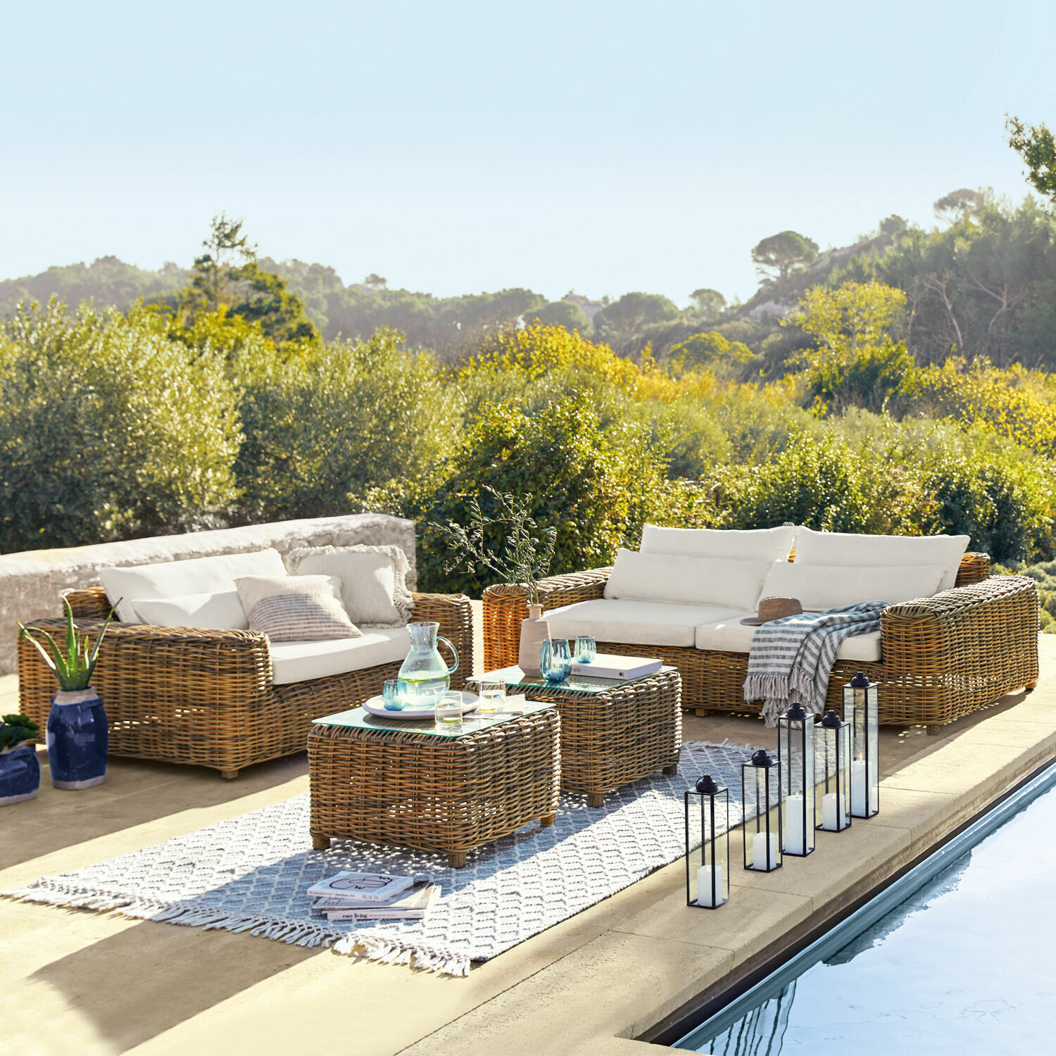 Gartenmöbel-Set aus natürlichem Rattan mit weißen Kissen neben dem Pool