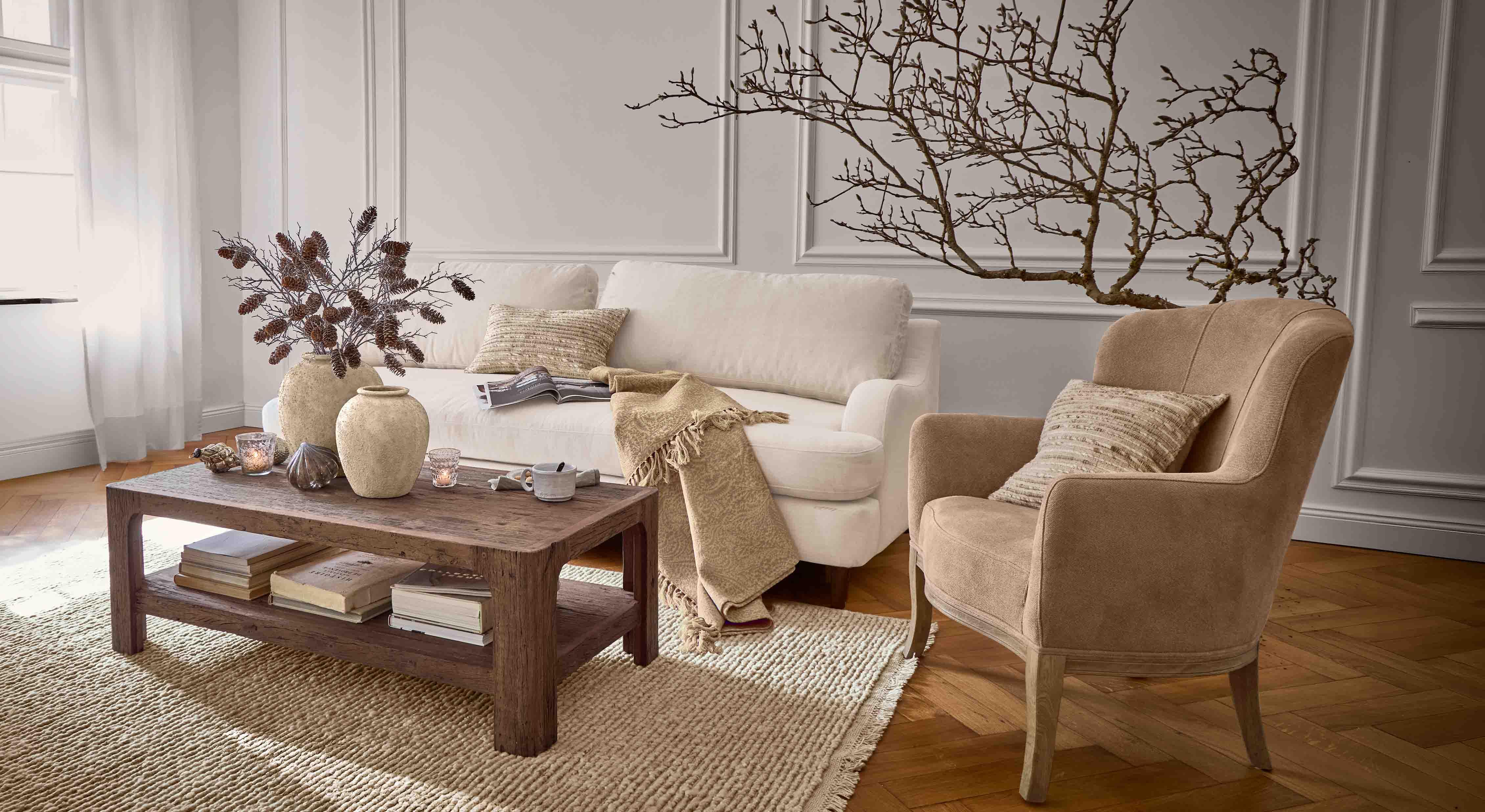 Gemütliches Wohnzimmer mit beigem Sofa, braunem Sessel und Holztisch auf gewebtem Teppich