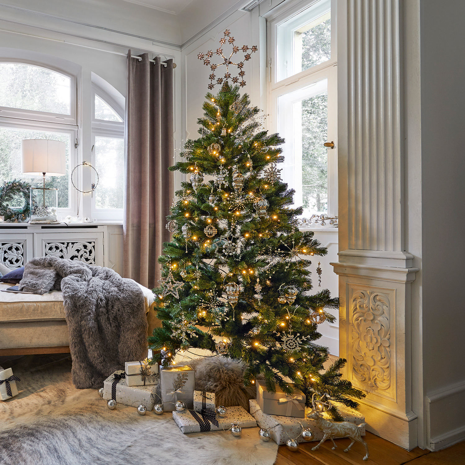 Weihnachtsbaum Helford Weihnachtsbaum mit grünen Zweigen und goldenen Dekorationen im hellen Wohnzimmer mit Geschenken