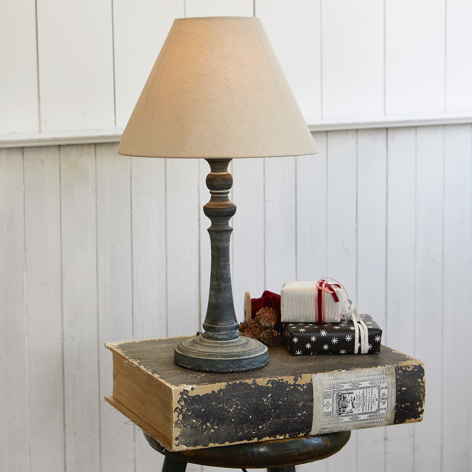 Tischlampe Withby Tischlampe mit beigem Lampenschirm und antikem schwarzen Fuß vor weißer Wand
