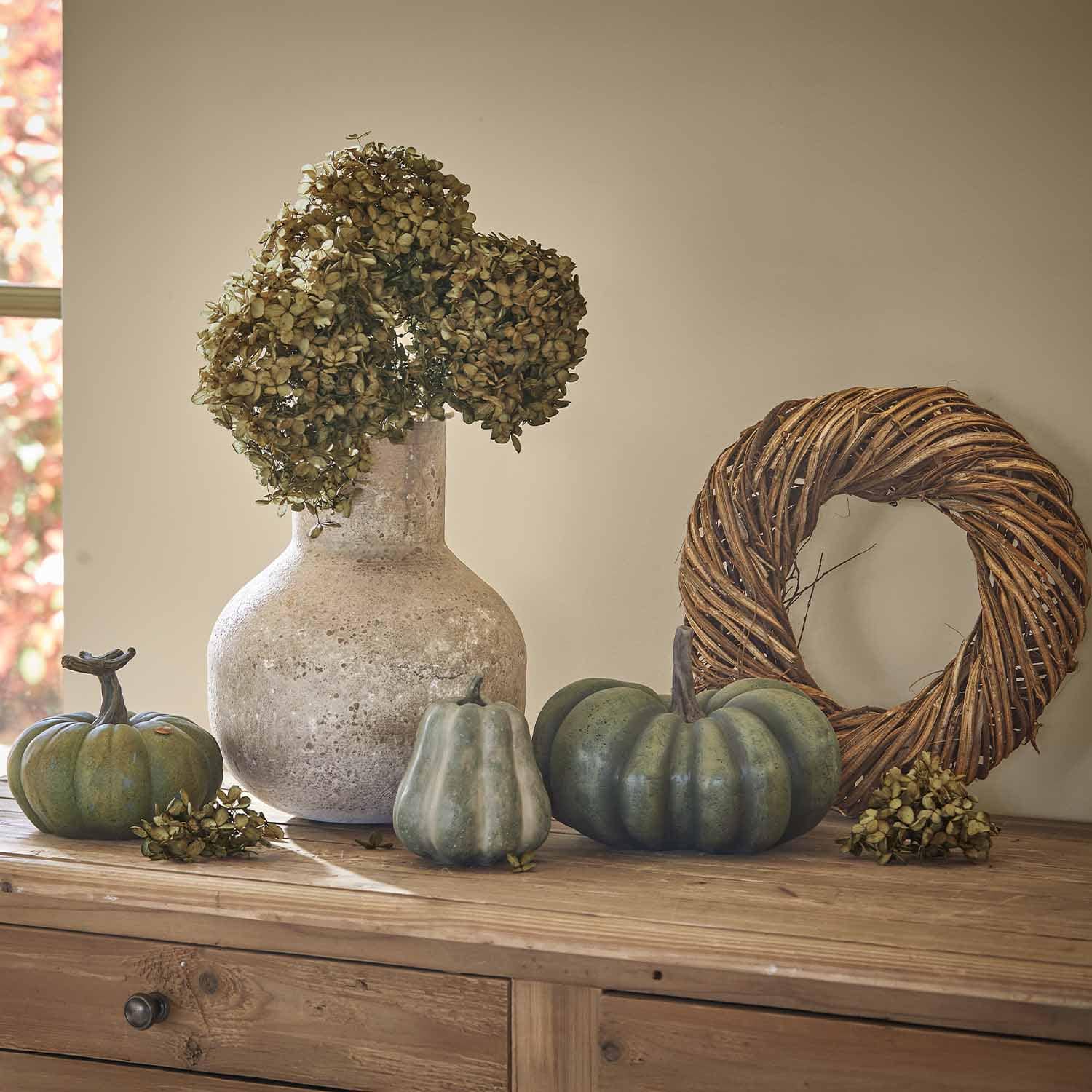 Steinvasen-Dekor mit getrockneten Blumen und grünen Kürbissen auf einem Holztisch