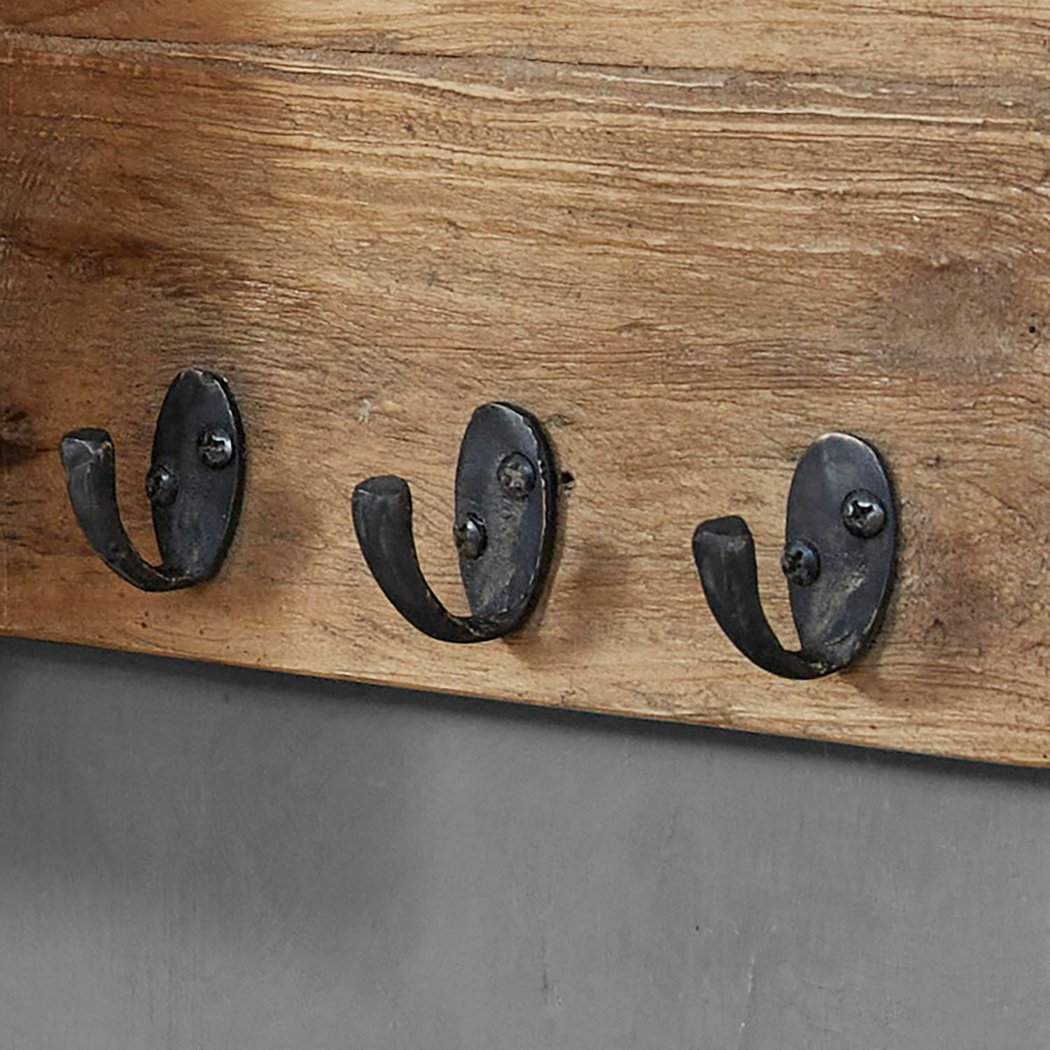 Drei schwarze Metallhaken an Holzbrett zur Aufbewahrung von Kleidung und Accessoires