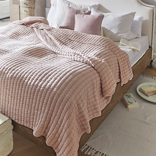 Rosa gesteppte Decke auf Holzbett mit weißen Kissen in gemütlichem Schlafzimmer