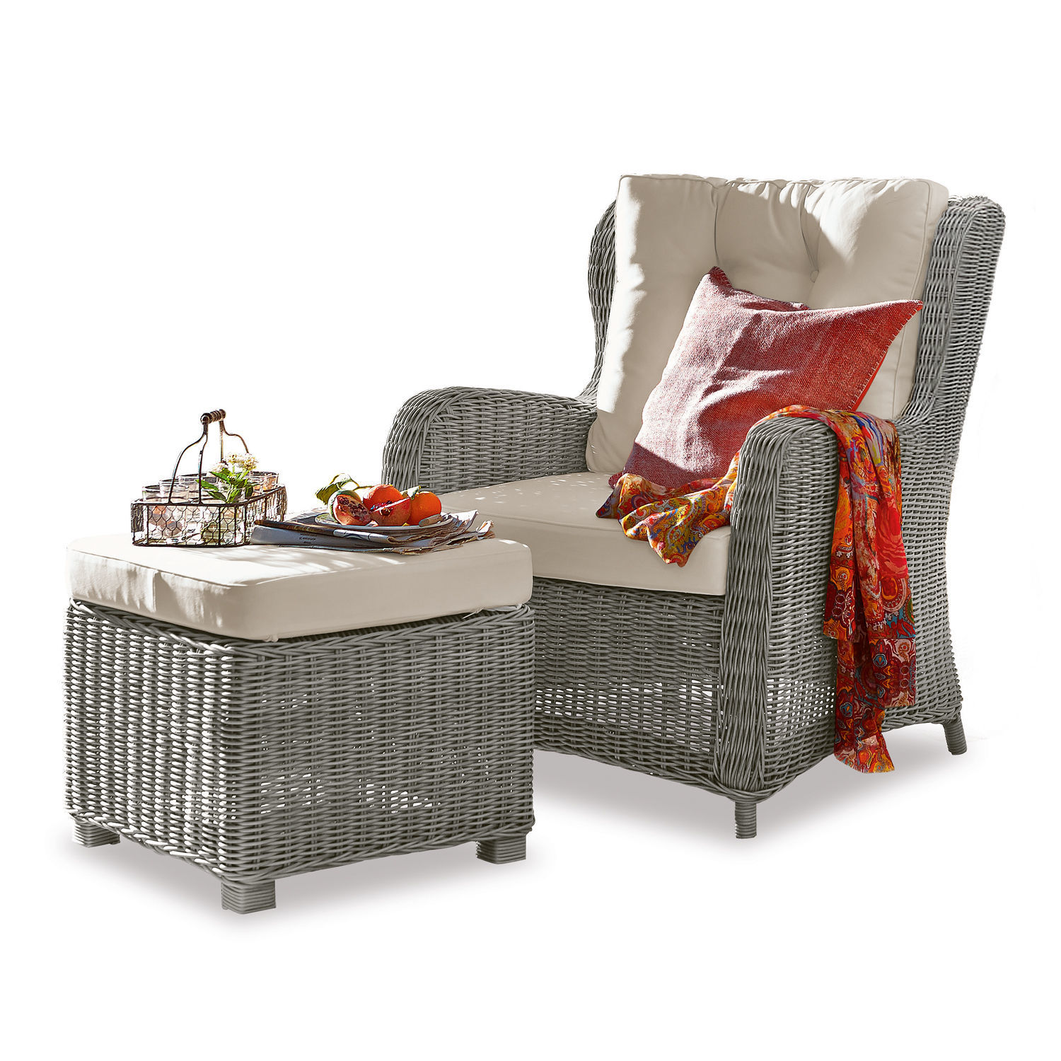 Grauer Rattan-Sessel mit cremefarbenen Polstern und Hocker, dekoriert mit rotem Tuch und Kissen