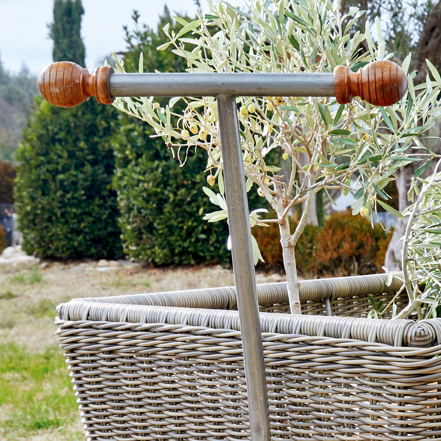 Metallgriff mit Holzenden an grauem Korb aus Rattan mit Pflanze im Garten