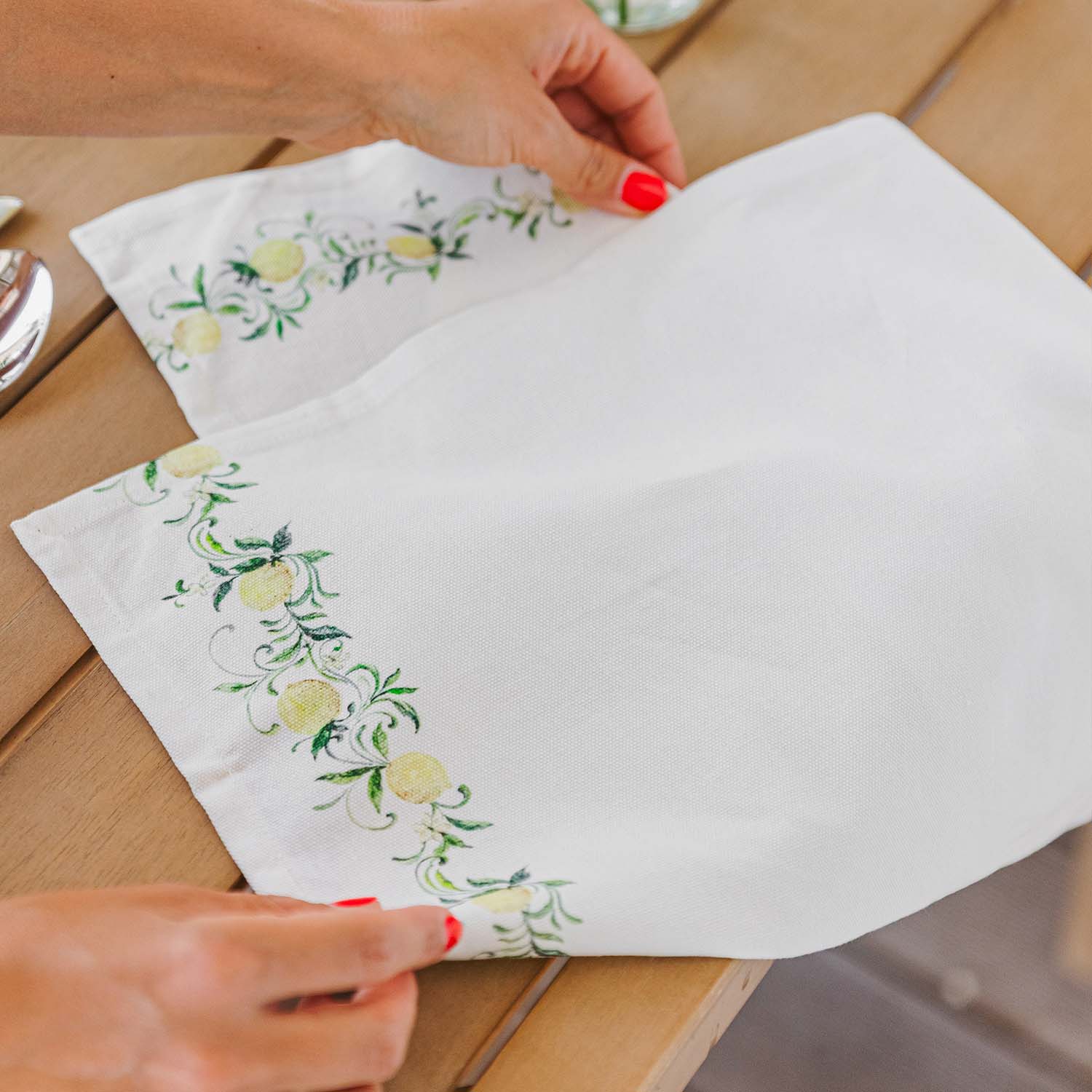 Weiße Leinenserviette mit grün-gelbem Zitronenmuster auf Holztisch, Tischdekoration