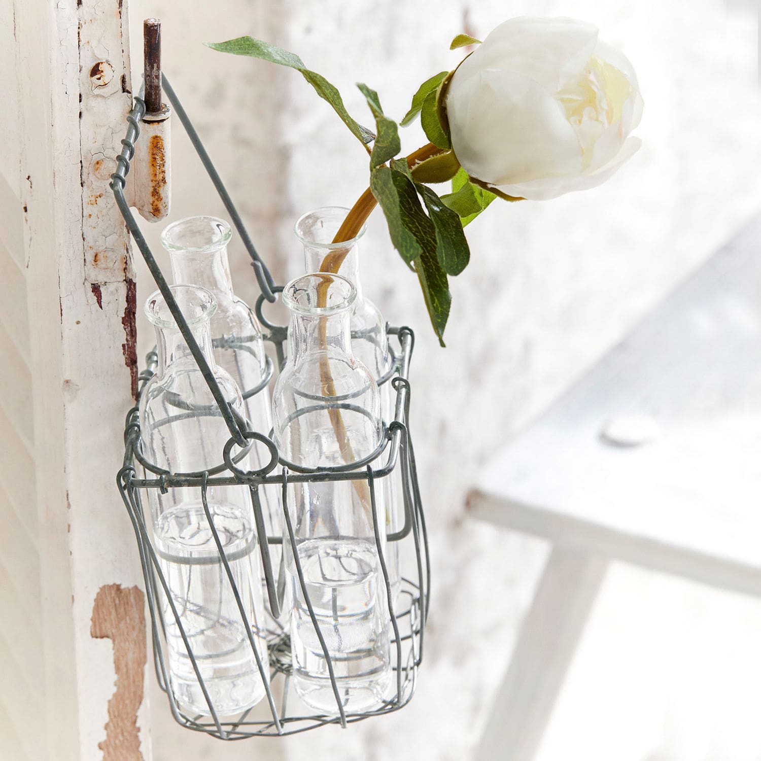Glasflaschen im Metallkorb mit weißer Blume, Vintage-Dekoration im Landhausstil