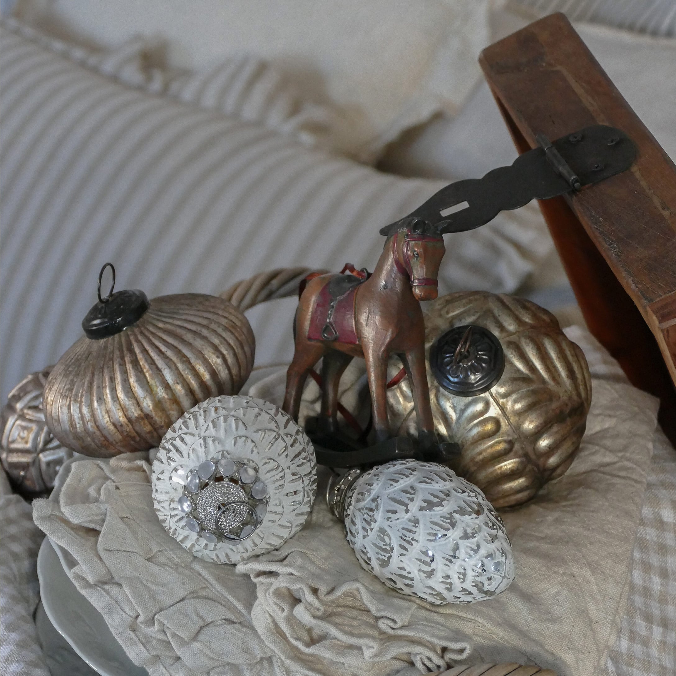 Gold-weiße Weihnachtsdekoration mit Pferdefigur auf beigem Stoff arrangiert