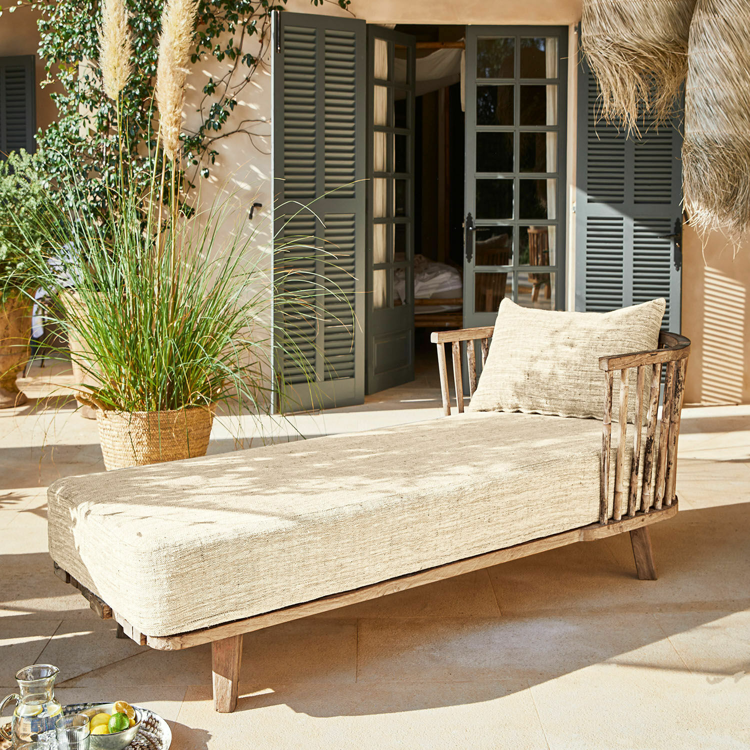Liege aus Holz mit beigem Stoffbezug auf sonniger Terrasse, Gartenmöbel zum Entspannen