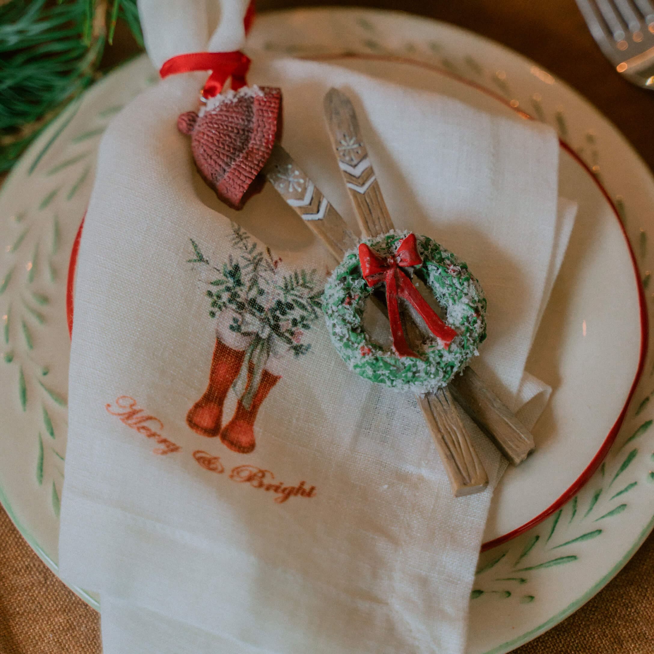 Weihnachtliche Tischdekoration mit weißem Leinenserviette und Holzornamenten mit grünem Kranz