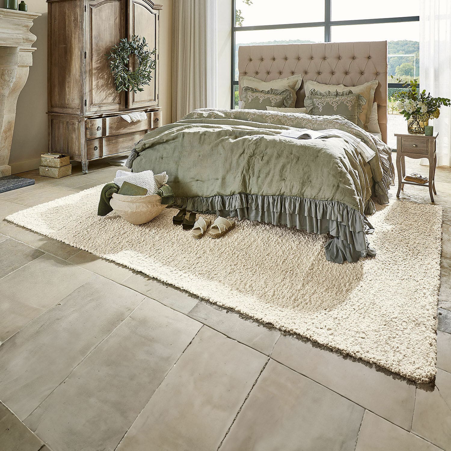 Teppich Wodaha Gemütliches Schlafzimmer mit beige gepolstertem Bett und grüner Bettwäsche auf cremefarbenem Teppich auf Steinboden