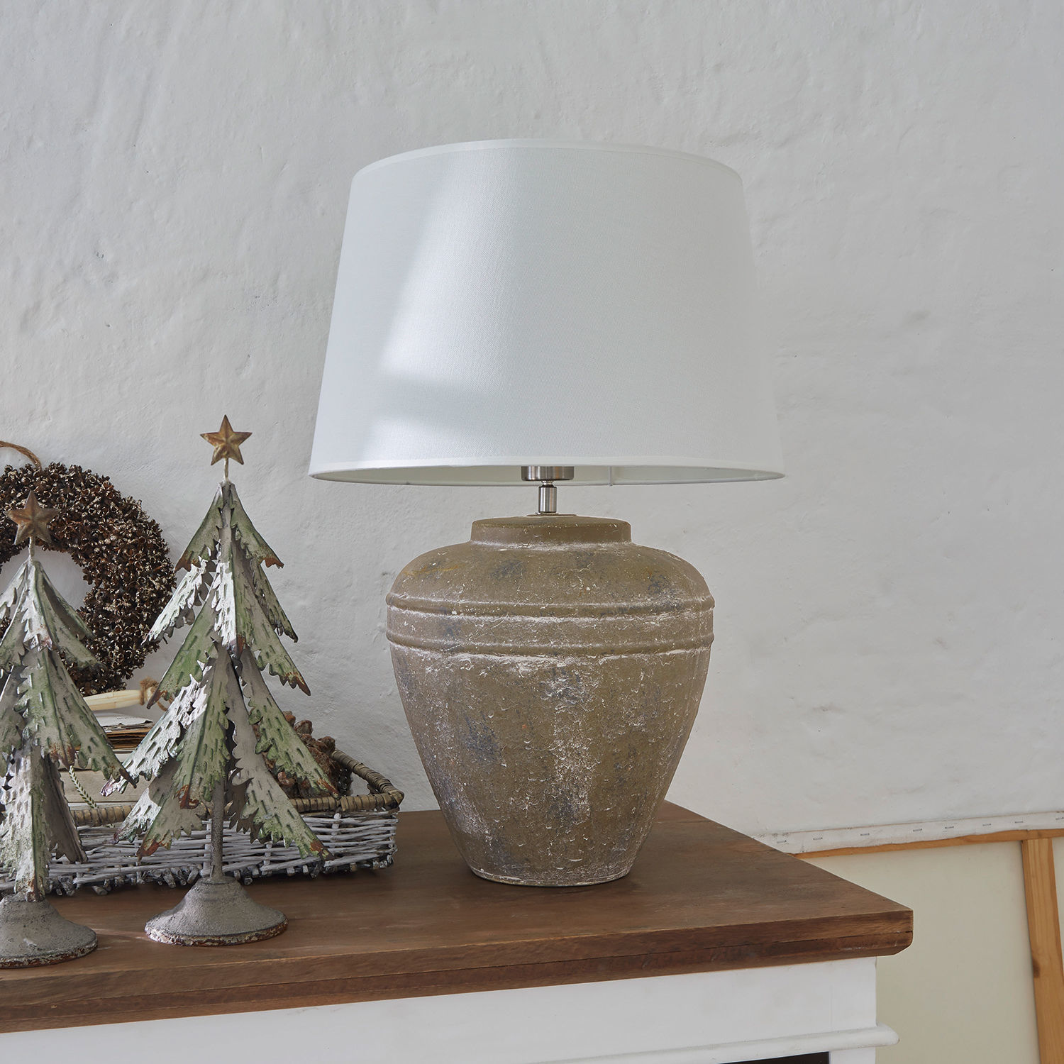 Tischlampe mit weißem Lampenschirm und brauner Keramikbasis auf Holzplatte