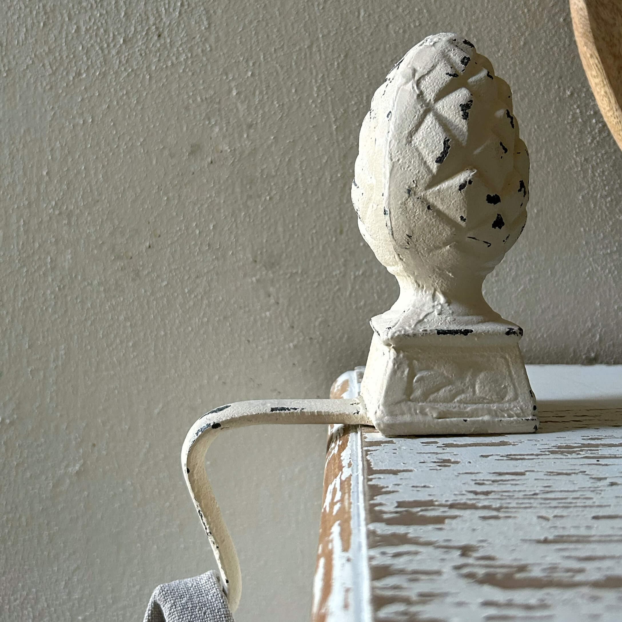 Weißer Metallgriff mit Zapfenornament auf antikem Holzmöbel mit Patina